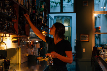lateral view of  frontal view of beautiful girl bartender working behind the bar