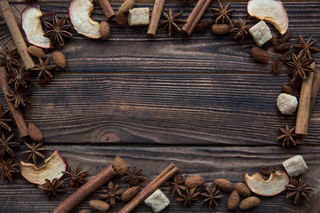 Tasty spicy autumn background, dried apple, cinnamon sticks, anise stars, brown sugar pieces, raisins, almond on brown table, rustic wooden table, top view, copy space. Thanksgiving background.