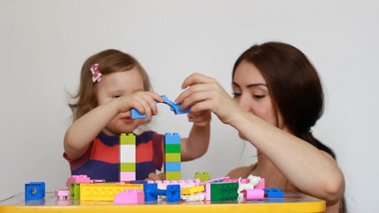Mother and girl child busy building a constructor.