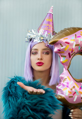 Young woman with party hat and balloon blowing a kiss