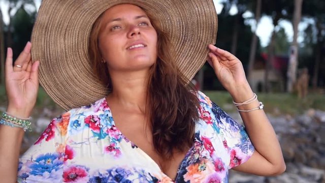 Tanned girl with big breast in a hat, posing on camera, against the backdrop of palm trees. slow motion, HD, 1920x1080