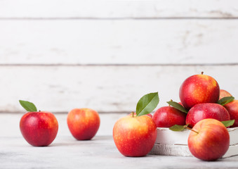 Braeburn pink lady apples in wooden box on white wooden background