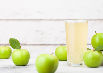 Glass of fresh organic apple juice with granny smith and british bramley apples in box on wooden background with sun light