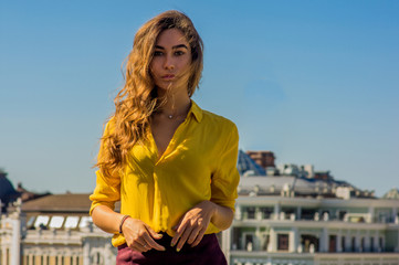 Fashion portrait of a young woman on the city landscape and blue sky background