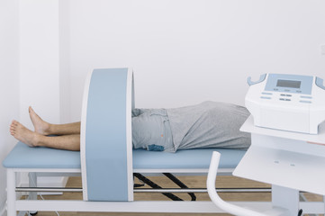 The physiotherapist treating a man using equipment for radio therapy