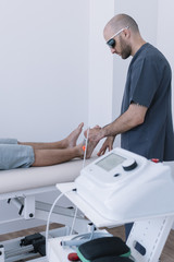 The physiotherapist treating a man using equipment for Lightning Laser