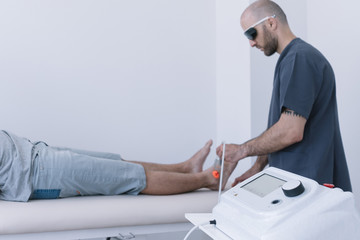 The physiotherapist treating a man using equipment for Lightning Laser