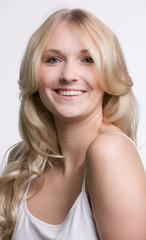 Fototapeta premium Junge hübsche blonde Frau im weissen Shirt lächelt sympathisch