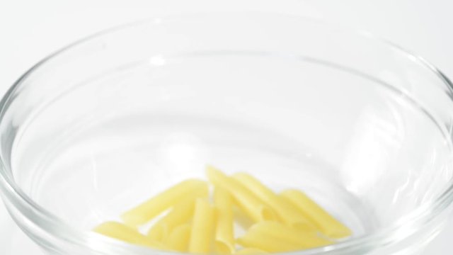 Llenando un bol de pasta penne cruda, detalle