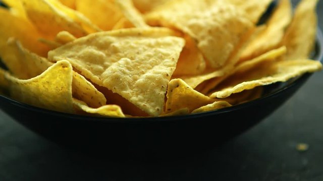 Closeup shot of bowl filled with crispy golden nacho chips and served on table in daylight