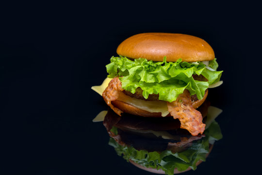 Fresh bacon cheeseburger on a reflective surface