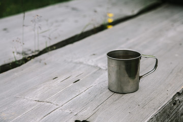a silver metal traveler's tourists mug stands on a wooden table with space for text