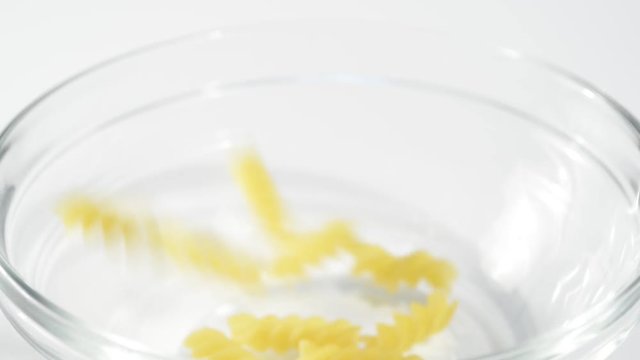 Llenando un bol de pasta espiral cruda, detalle