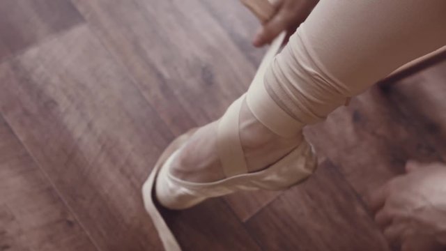 Close-up of ballerina's legs with pointe shoes. Dancer wears ballet slippers. Prepare for the dance. Interior studio in the old style. Natural lighting with haze.