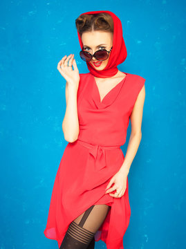 portrait of pin up girl in red dress on blue background
