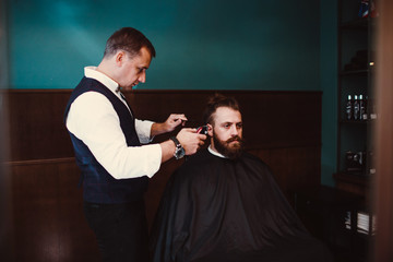 Barbershop with wooden interior. Bearded model man and barber.
