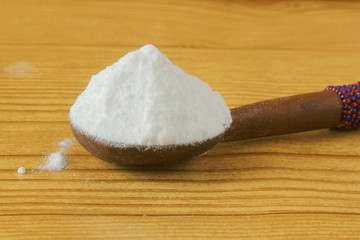 baking soda or baking powder in spoon isolated in wooden background for cooking recipe or cleaning
