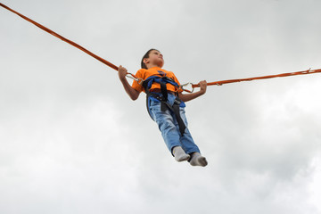 happy young boy jumping on bungee trampoline