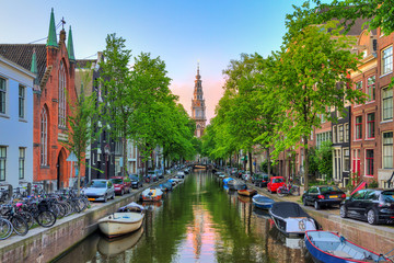 Schöner Groenburgwal-Kanal in Amsterdam mit der Südkirche (Zuiderkerk) bei Sonnenuntergang im Sommer
