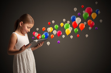 Cute little girl using tablet with colourful balloons concept

