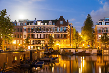 Fototapeta na wymiar Beautiful cityscape of the famous canals of Amsterdam, the Netherlands, at night with a mirror reflection and a full moon