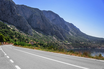 Fototapeta premium Asphalt highway in a sunny day. Asphalt highway in a sunny day outside the city passing through the cliff.
