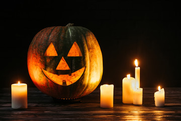 scary jack o lantern with candles on wooden table on black background