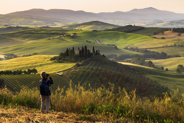 Fototapeta na wymiar Photographing at sunrise beautiful Tuscany landscape with traditional farm house, hills and meadow. Val d'orcia, Italy.