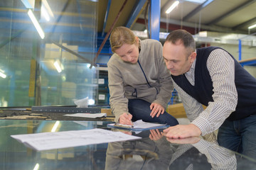 male and female manual workers examining paper in industry