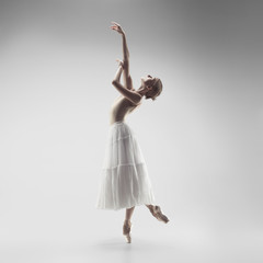 Young graceful female ballet dancer or classic ballerina dancing on white studio. Caucasian model...