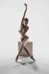 Young graceful female ballet dancer or classic ballerina dancing on white studio. Caucasian model...