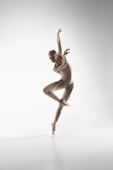 Young graceful female ballet dancer or classic ballerina dancing on white studio. Caucasian model...