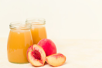 Peach smoothie in glass jars with fresh ripe fruits on yellow pastel background.