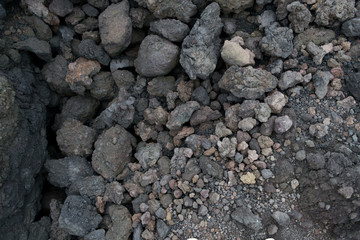 Texture of the dark land of the slopes of the mount Etna. An active volcano in Sicily Etna. People hike up this famous place to see this unusual landscape.