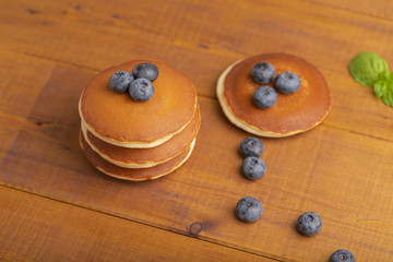 A stack of American pancakes or pancakes with blueberries and mint on a wooden table. Delicious dessert for Breakfast.