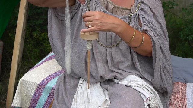 Woman spinning with a wheel. A woman makes yarn from a sheep's wool