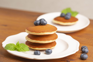 Delicious close-up pancakes with fresh blueberries and mint on a white plate