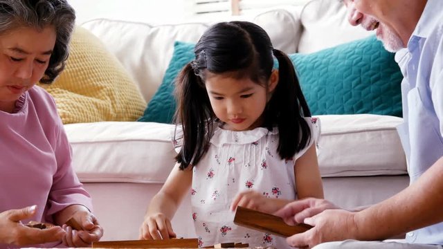 Senior man woman and little girl playing board game together at home. people with family, lifestyle, education concept. 4k resolution.
