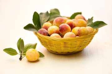 Mirabelle plum. Fresh berries in a small yellow basket. Poroschiya for tasting.