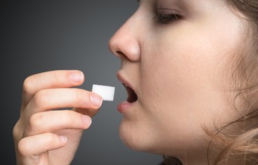 Woman is swallowing cube of sugar. Unhealthy eating concept.