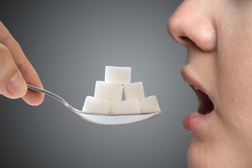Woman addicted on sugar is eating spoon full of sugar blocks. Unhealthy eating concept. - obrazy, fototapety, plakaty