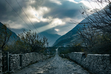 Dust road connecting Jomson with Marpha in Annapurna Circuit and sunshine passing through the clouds, Himalayas