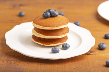 Delicious close-up pancakes with fresh blueberries and mint on a white plate