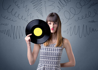 Young lady holding vinyl record on a grey background with scribbles around her