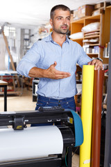 Man printing worker with rolls of colored paper