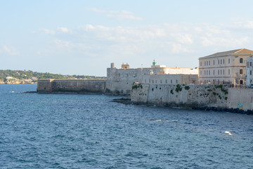 Fototapeta na wymiar The gorgeous seafront of the island of Ortigia, in the city of Siracuse, Sicily(Italy). In this shot taken from a boat you can see the old city walls and the Maniace castle built in the 13th century.