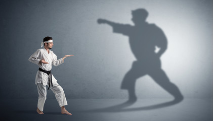 Young karate man confronting with his own shadow
