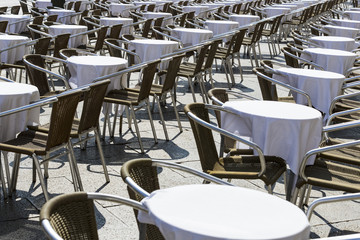 Rows of tables and chairs on the street in a restaurant 