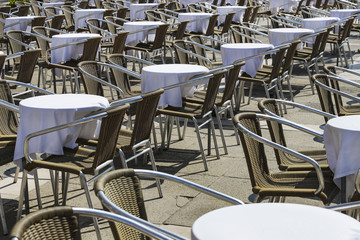 Rows of tables and chairs on the street in a restaurant 