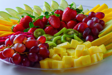 Fruit platter with fresh grapes, apple, pineapple, kiwi, mango, red ripe strawberry and pitaya. Colorful Fruit tray best health good food for party and holidays table.